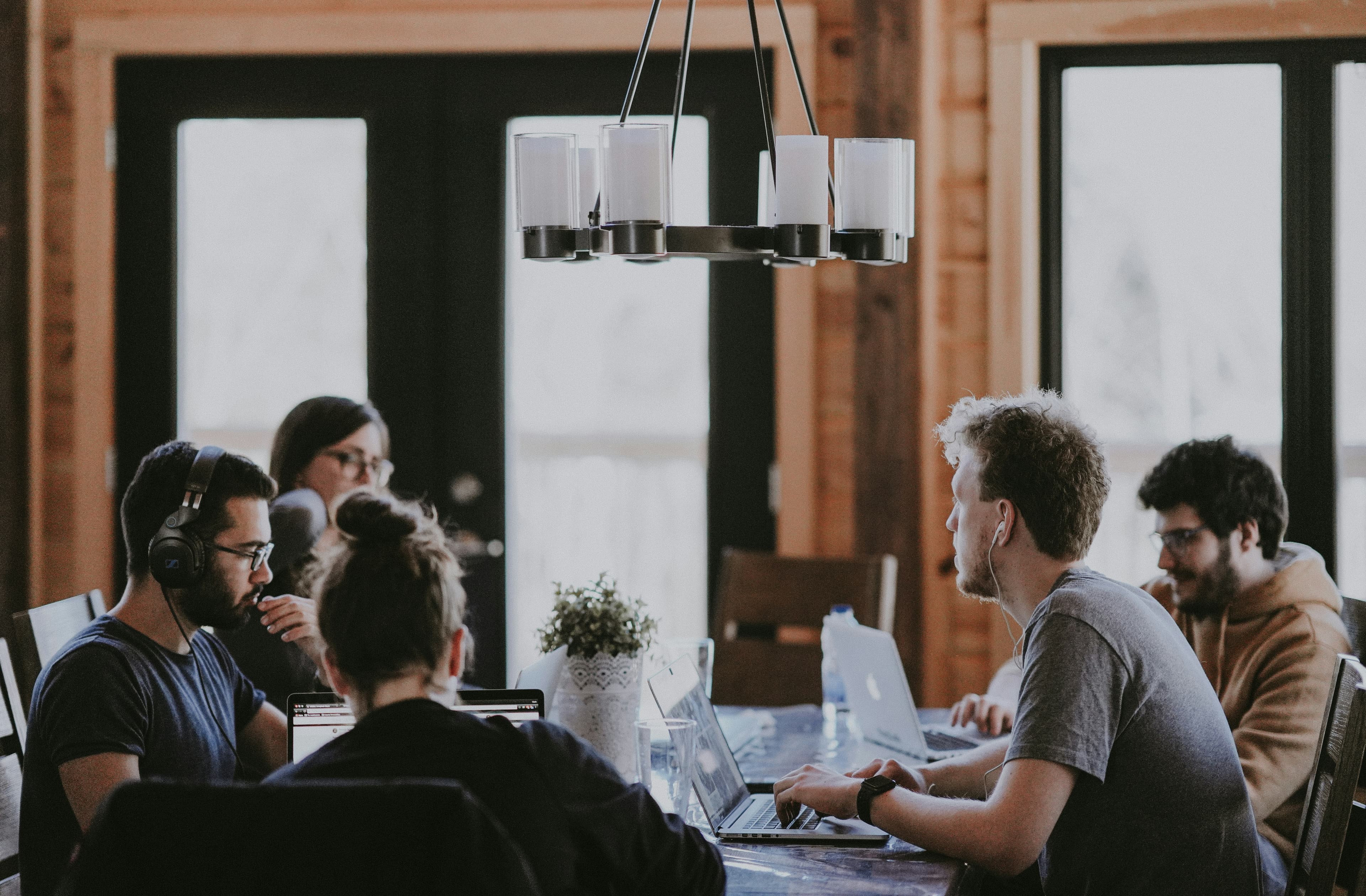A small team meeting around a table with laptops open