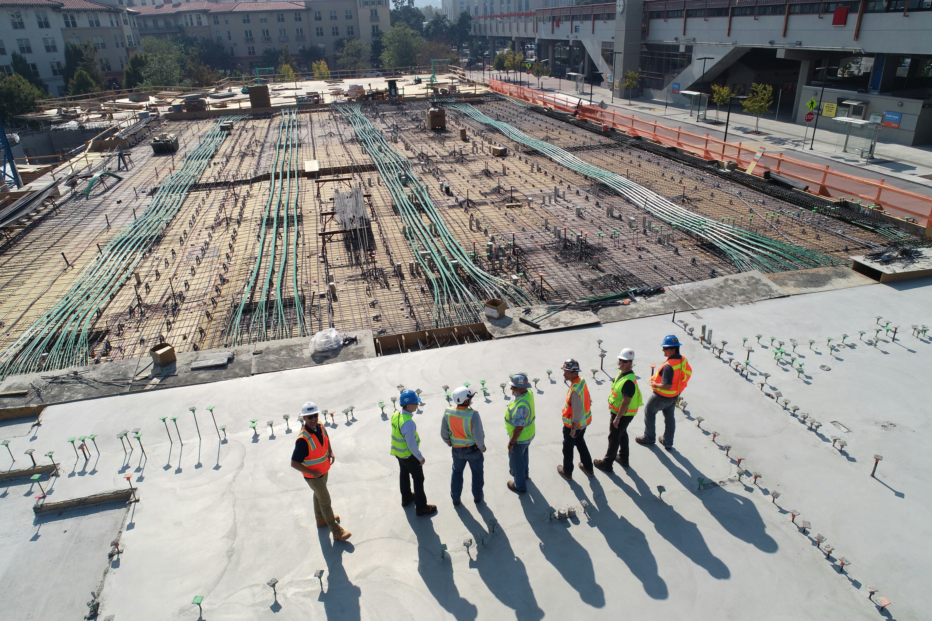 A crew in hard hats reviewing a large-scale construction site from above